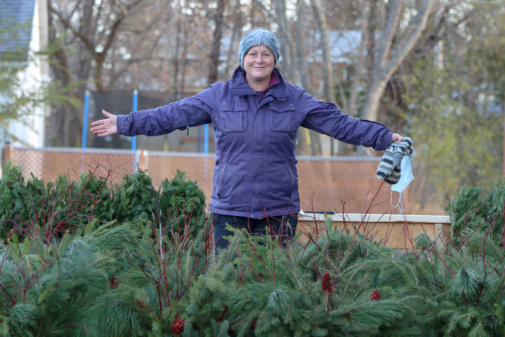 Executive Director Dawn Rodger standing in the forest of handmade wreaths and planters
